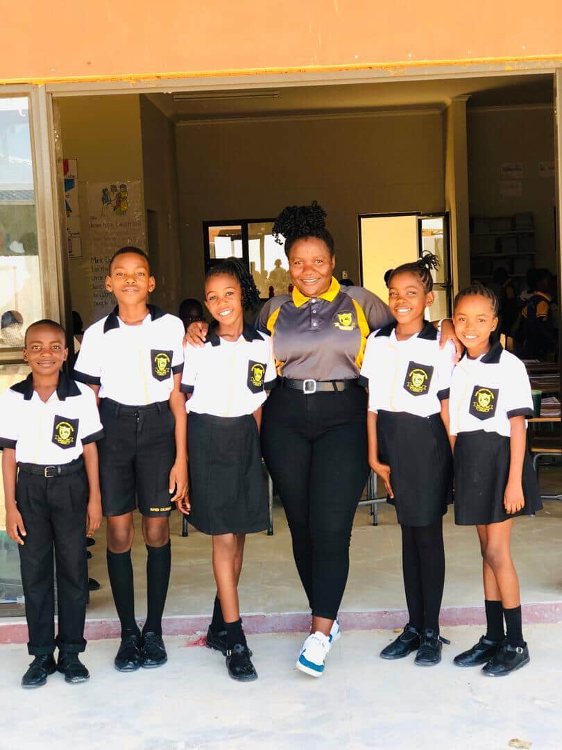Teacher standing with six learners in front of a classroom