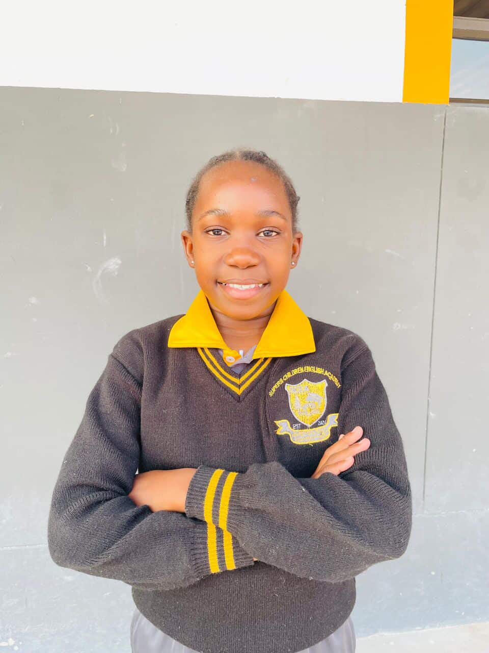 Learner in a Superb Children English Academy jersey smiling with arms folded