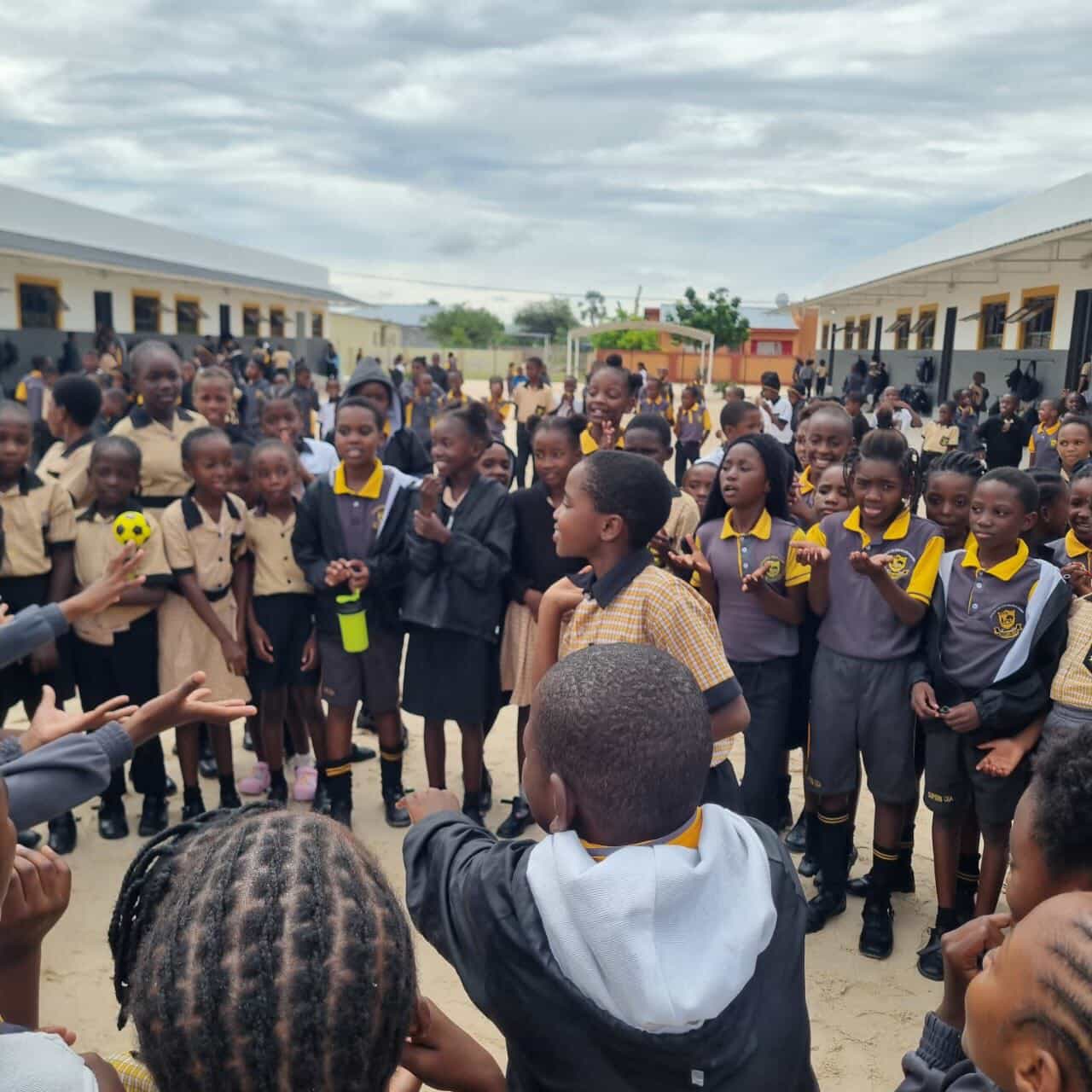 Learners gathered in a circle clapping and singing during break time