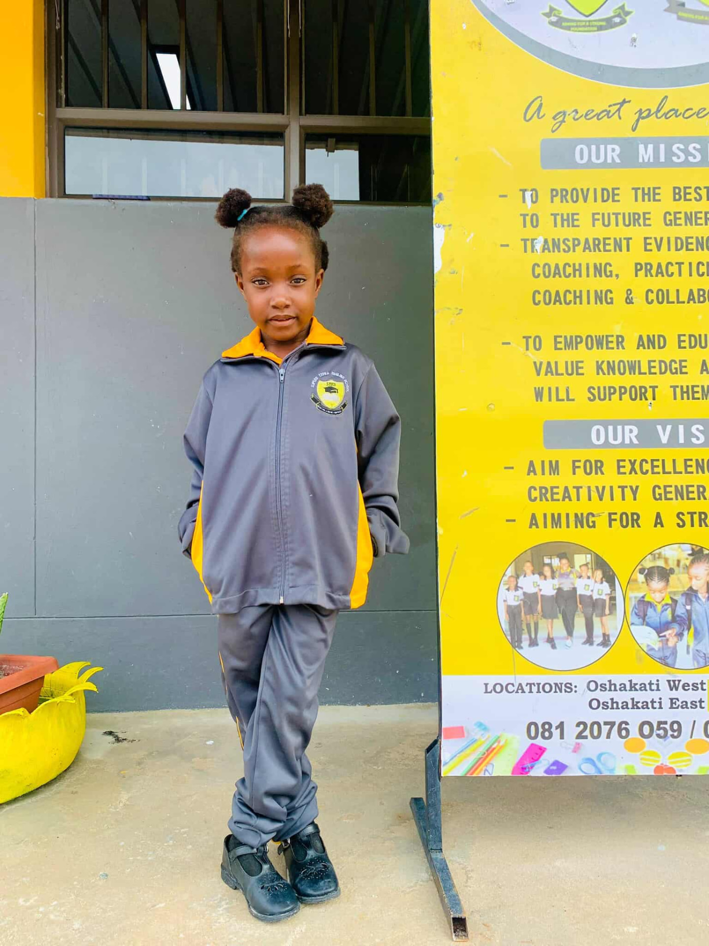 Learner standing beside the school's mission and vision banner