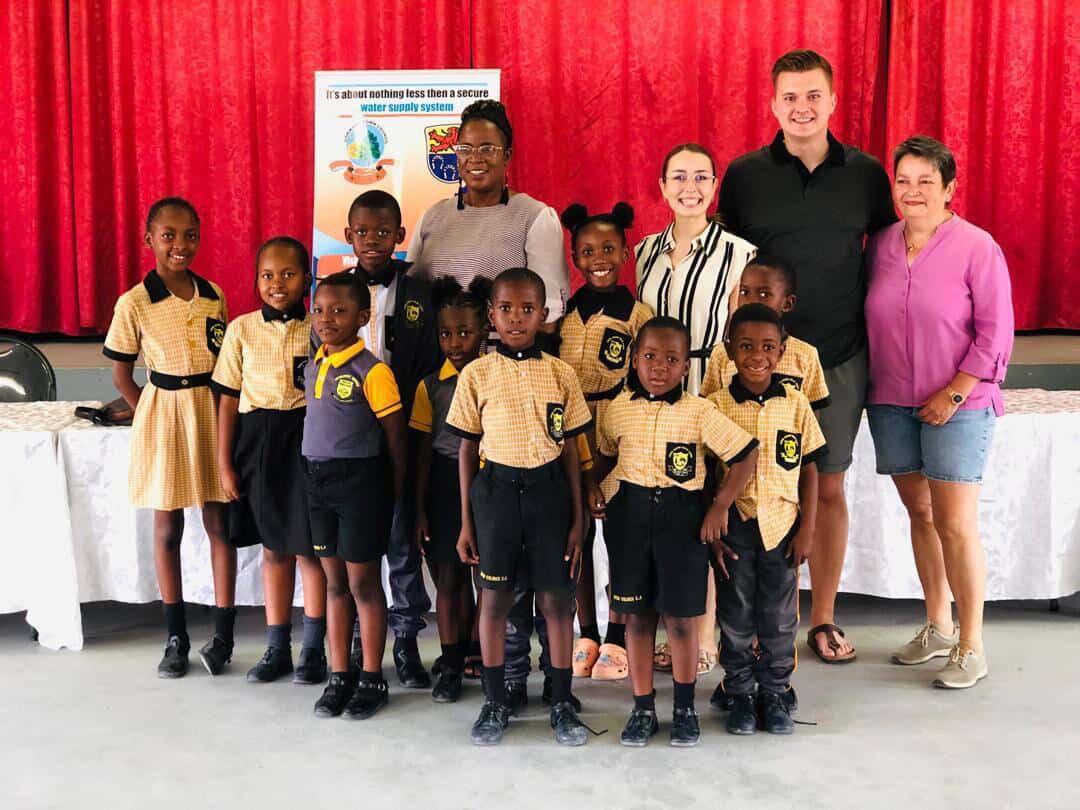 Learners and visiting partners posing together at a water supply awareness event