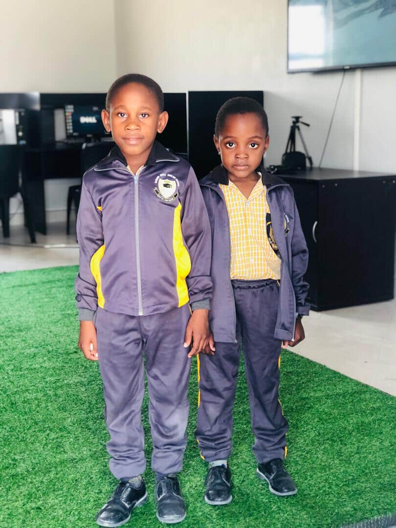 Two learners in tracksuits standing in the school computer room