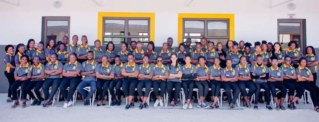 Full staff of Superb Group of Schools in grey and gold uniforms seated for a group photograph