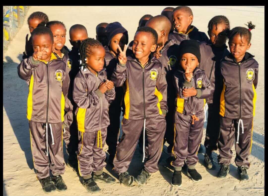 Group of preschool learners in tracksuits posing outdoors in the morning sun